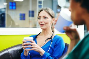 Female physician talking with colleagues during coffee break